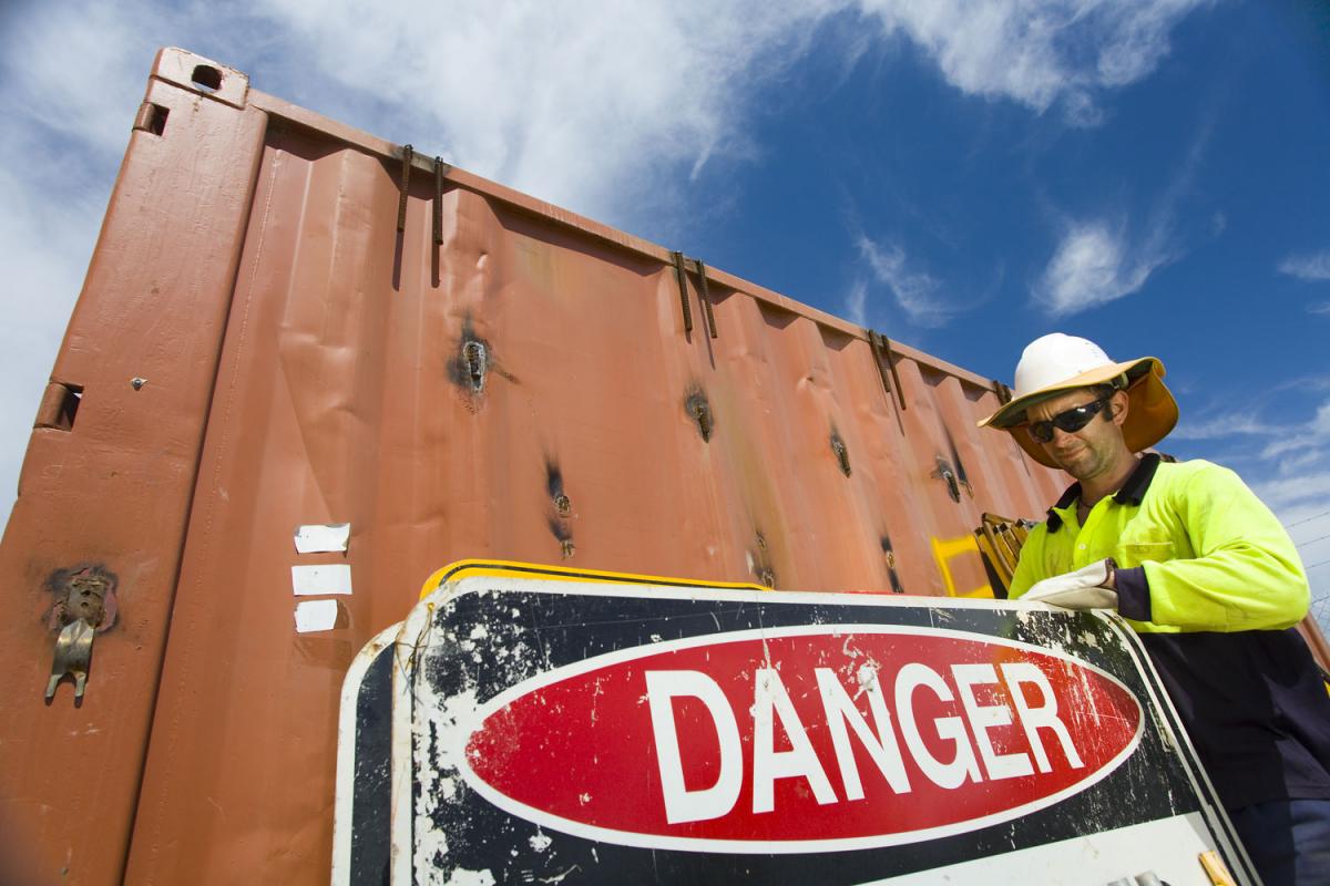Picture of a worker holding "Danger" sign